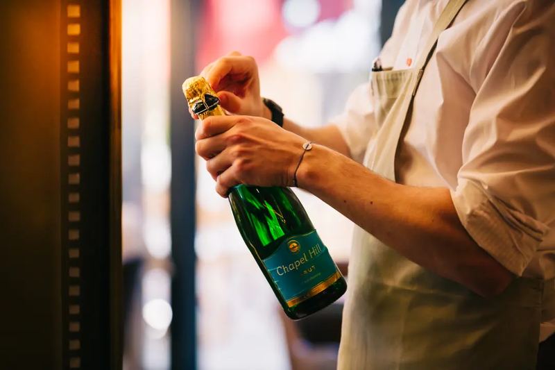 A waiter opening a Chapel Hill brut champagne at Hotel Kempinski Budapest