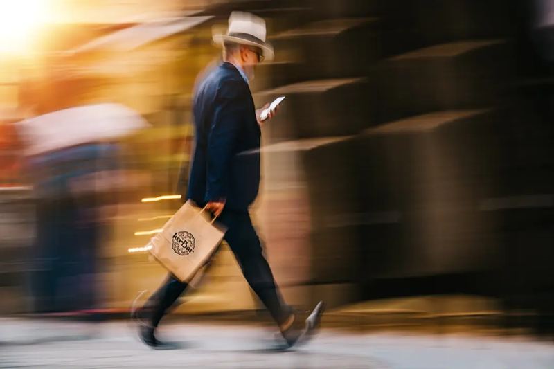 Businessman walking in a motion blur. Holding a paper bag