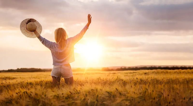 Lifestyle photography on a topic freedom. A lady standing freely in a wheat field