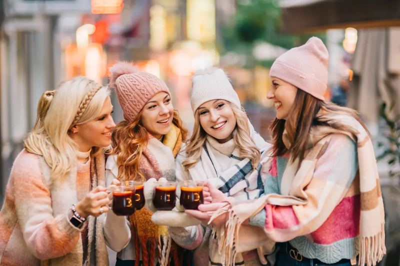 Candid photography of ladies having a mulled wine in the winter season